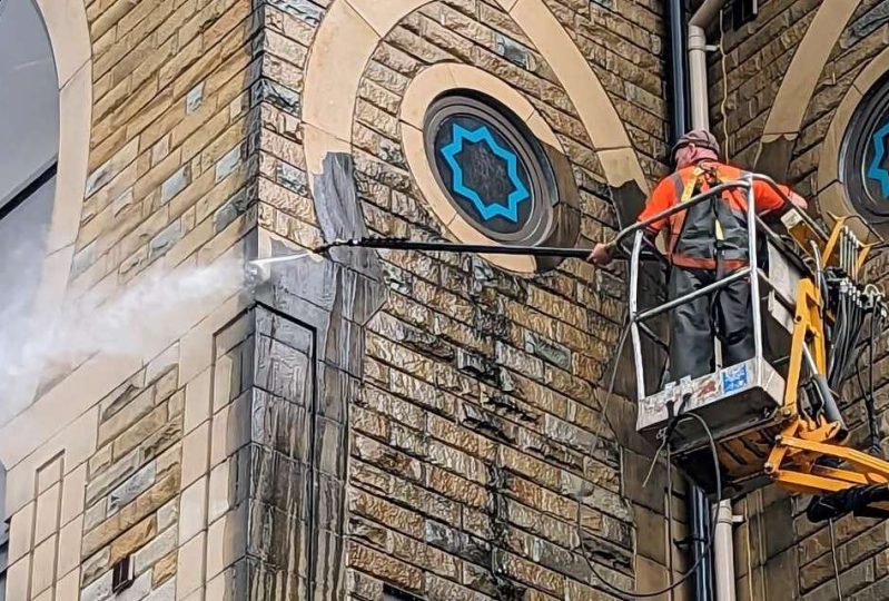 Cleaning an exterior of a building with the help of cherry picker and pressure washer